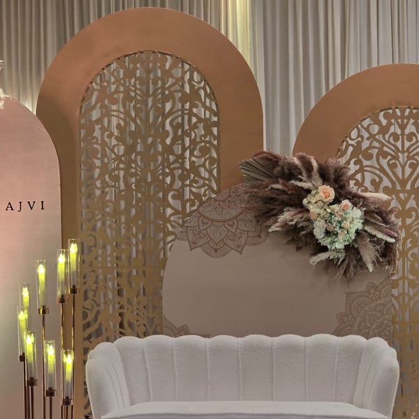 Elegant Indian-themed decor with arched screens, floral arrangements, candles, and a white sofa.