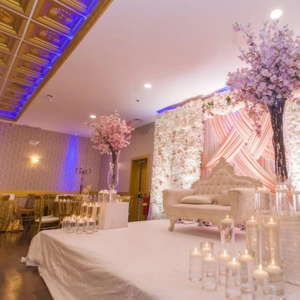 Elegant Indian wedding stage with a white sofa, floral backdrop, and floating candles.