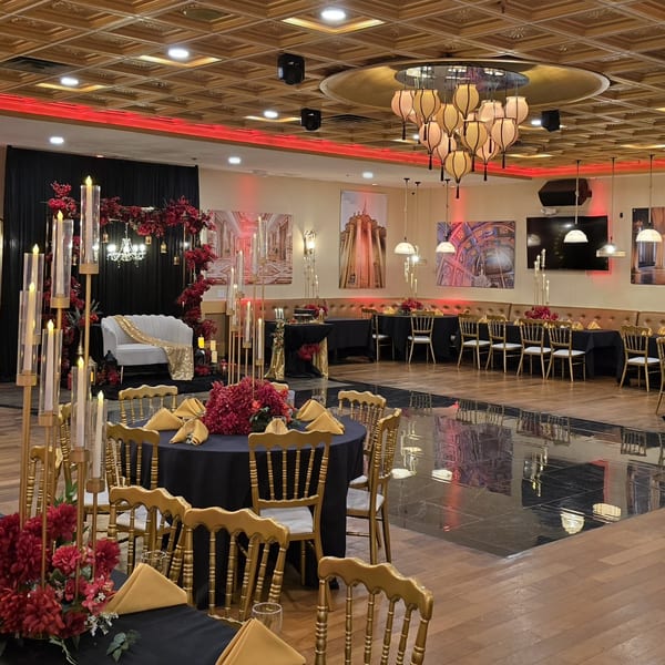 Elegant Indian restaurant interior with black and gold tables, red floral decor, and a white sofa.
