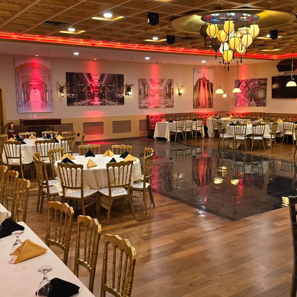 Elegant dining room at Spice Culture with gold chairs, white tablecloths, and red-lit Indian-themed artwork.
