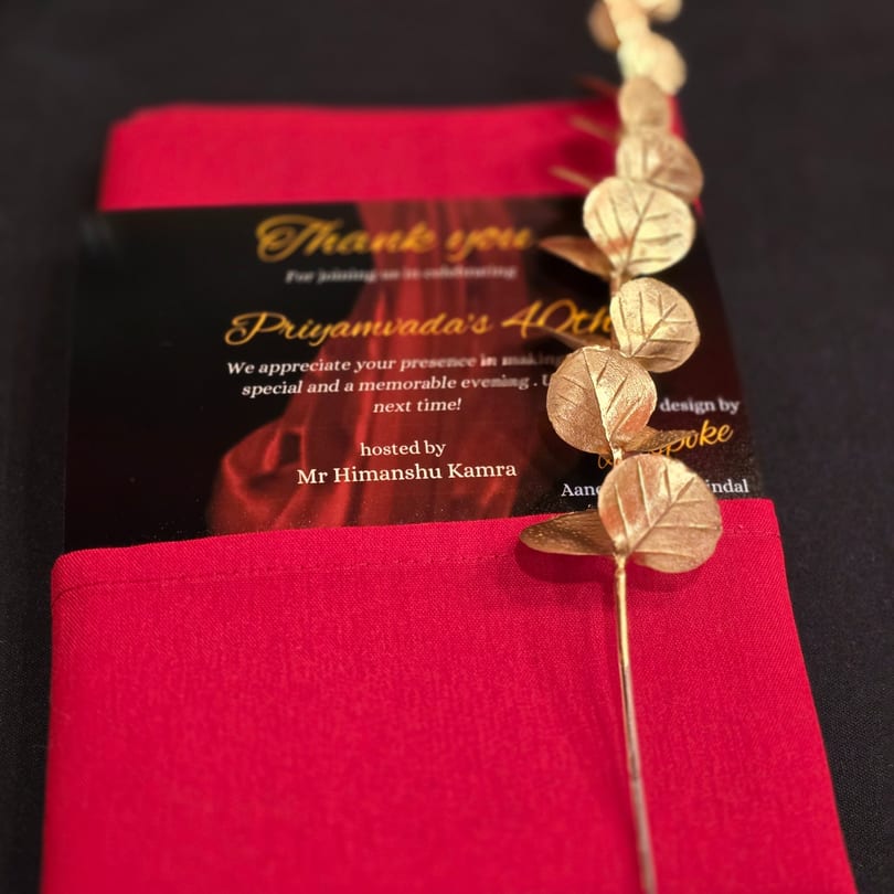 A black and red thank you card for Priyamvada's 40th birthday, adorned with golden leaf decorations.