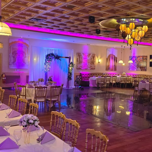 An empty Spice Culture dining room set for an event, with purple lighting and floral decor.