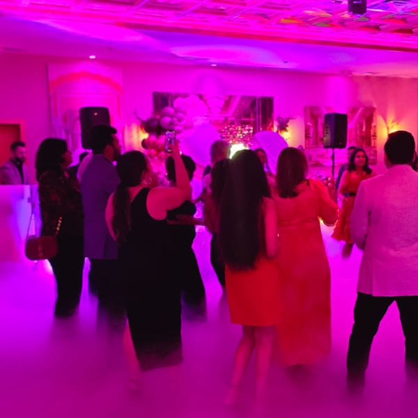 Guests dancing on a fog-covered floor under vibrant pink lighting at Spice Culture.