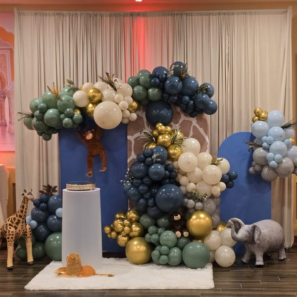 Safari-themed balloon arch with animal figures, including a giraffe, lion, elephant, and monkey.