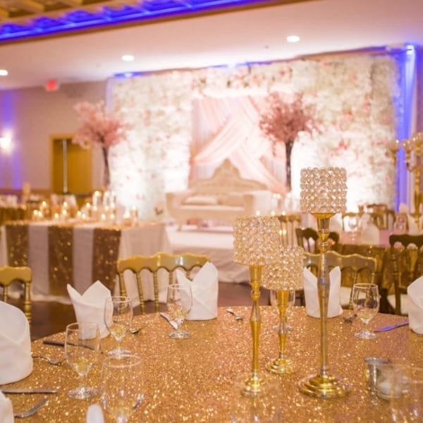 Elegant dining room with gold sequin tablecloths, crystal centerpieces, and a floral backdrop.
