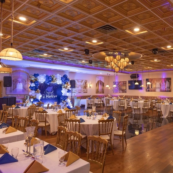 An empty Spice Culture dining hall set up for an event with round tables and a balloon arch.