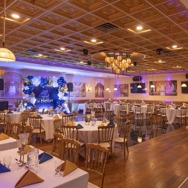 Elegant Indian restaurant interior with set tables, a balloon arch, and ornate ceiling details.
