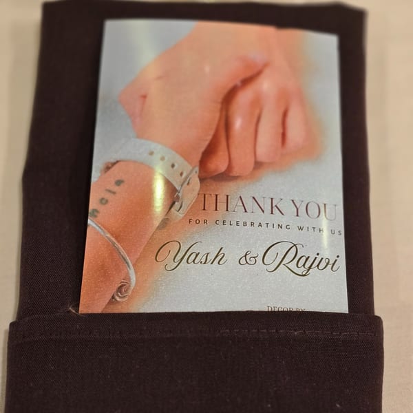 Thank you card for Yash & Rajvi, featuring two hands, tucked into a dark napkin.