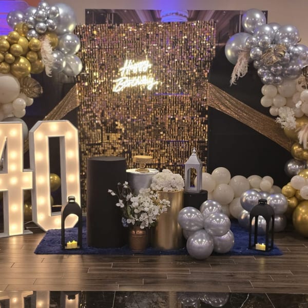 A festive birthday display with gold and silver balloons, a 'Happy Birthday' neon sign, and illuminated '40' numbers.