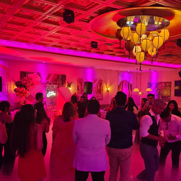 Guests dancing under red lighting and ornate gold chandeliers at Spice Culture Indian restaurant.