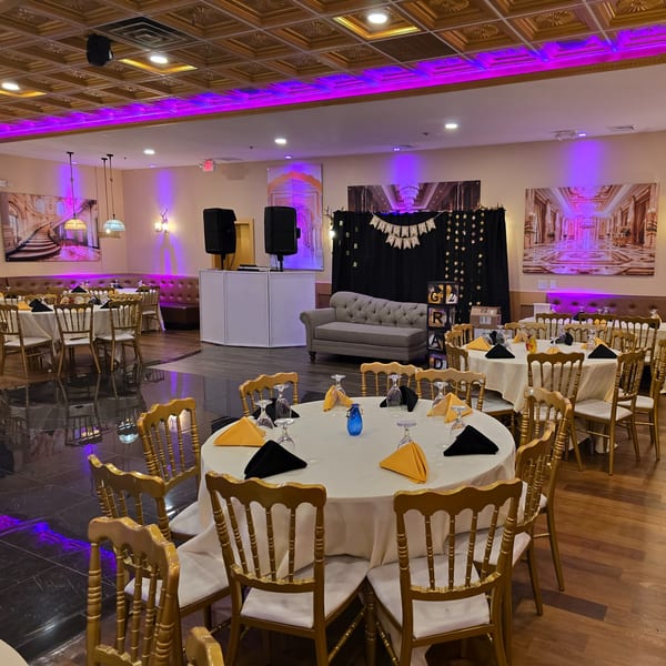 Elegant dining hall at Spice Culture with round tables, gold chairs, and purple accent lighting.