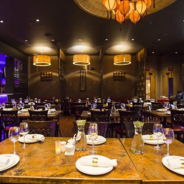 The elegant dining room of Spice Culture, featuring set tables, warm lighting, and decorative Indian lanterns.