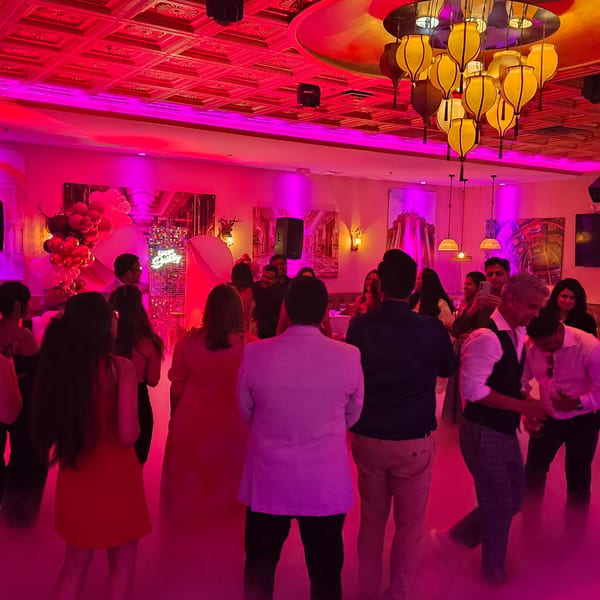 Guests dancing under pink lights and ornate lanterns at Spice Culture Indian restaurant.