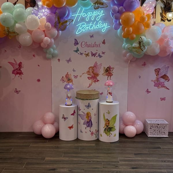 Pink wall with fairy and butterfly decals, balloons, and a "Happy Birthday Chaishvi" neon sign.