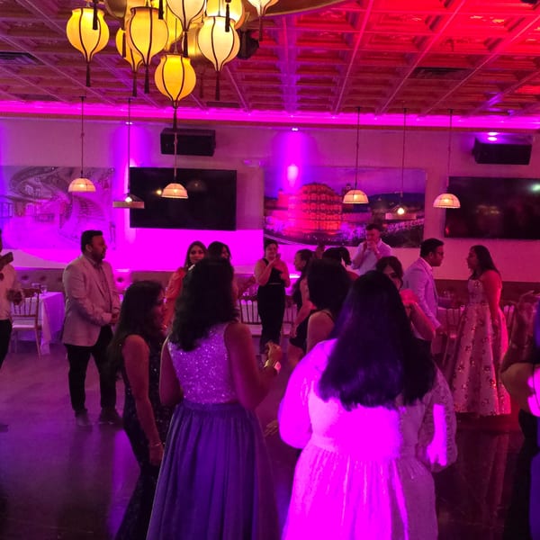 Guests dancing under vibrant pink and purple lights at Spice Culture, an Indian restaurant.