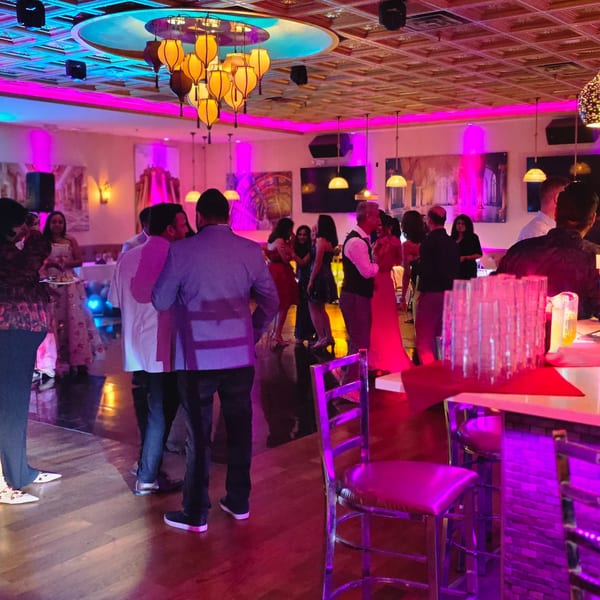 People socializing and dancing under colorful lights at Spice Culture Indian restaurant.