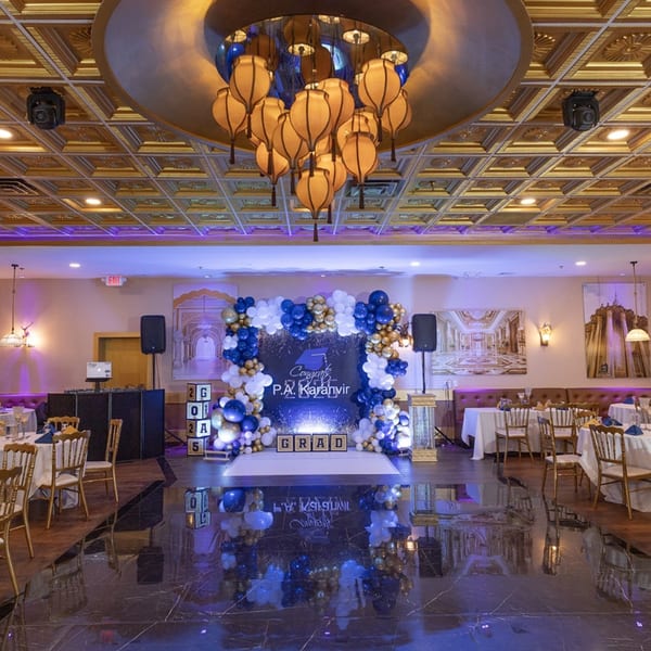 A large, elegant banquet hall at Spice Culture, decorated with blue and gold balloons for a graduation party.