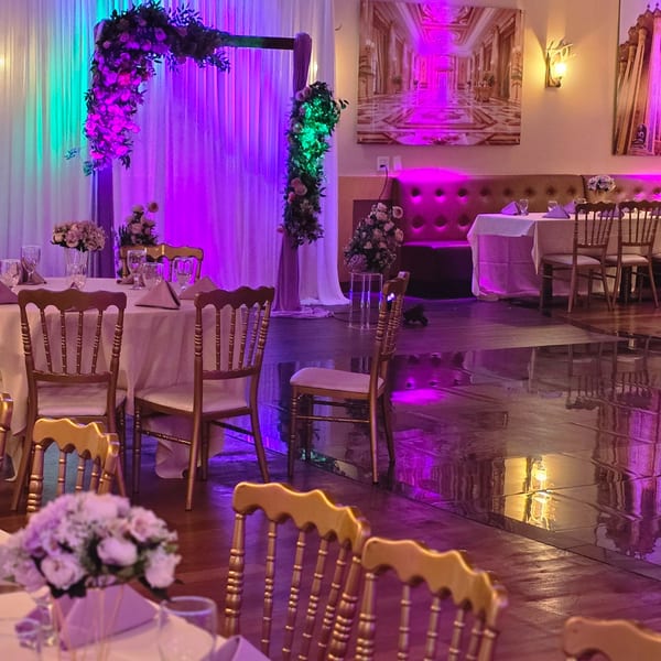 Elegant dining room at Spice Culture with tables, golden chairs, floral decor, and vibrant purple lighting.