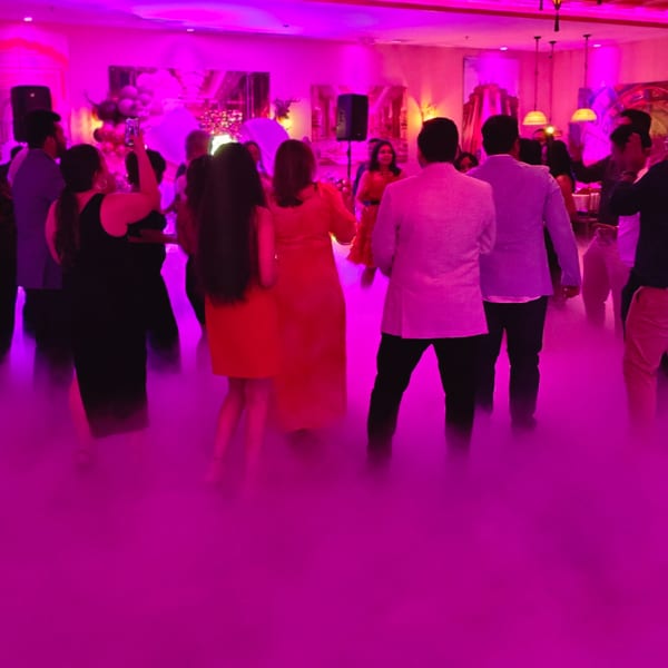 Guests dancing in a vibrant, fog-filled room with pink and purple lighting at Spice Culture.