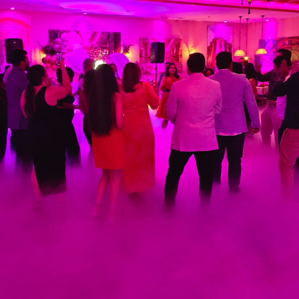 Guests dancing in a vibrant, fog-filled room with pink and purple lighting at Spice Culture.