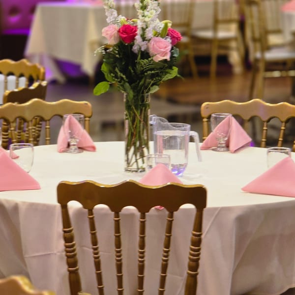 Elegant dining table set with pink napkins, water glasses, and a floral centerpiece at Spice Culture.