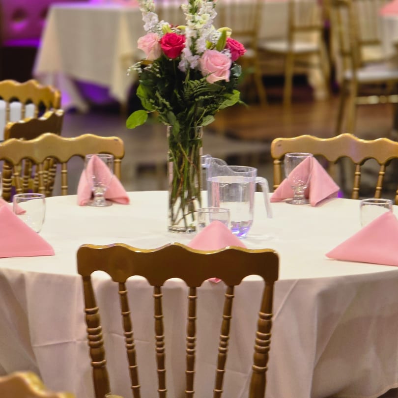 Elegant dining table set with pink napkins, water glasses, and a floral centerpiece at Spice Culture.
