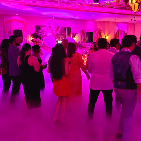 Guests dancing in a vibrant, pink-lit room with fog on the floor at Spice Culture.